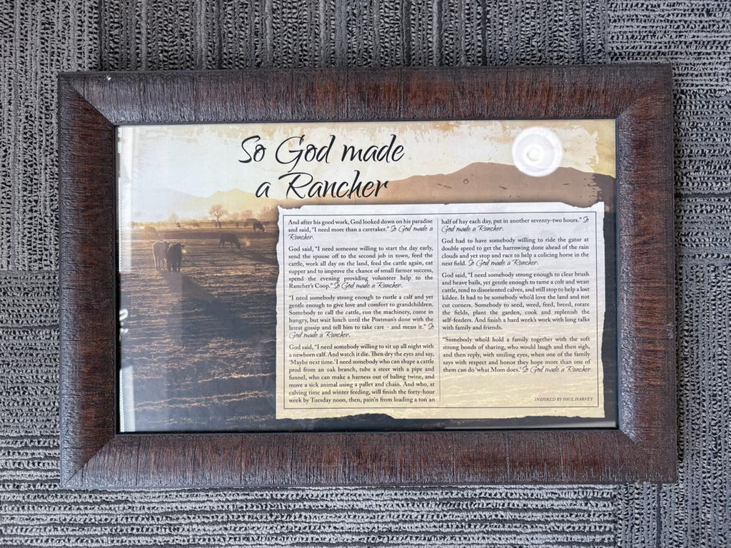 A framed decorative piece featuring a Bible verse printed on aged beige paper, with the phrase 'So God made a Rencher' in script on the left, set in a dark brown wooden frame on a gray textured fabric background.